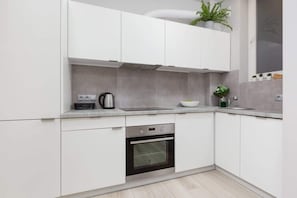 A stunning kitchen design featuring white cabinets with brass handles, a pristine white tiled backsplash, and open shelving for an organized and stylish look. Ideal for cooking enthusiasts seeking both functionality and aesthetics.