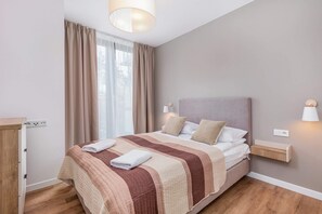 Cosy bedroom with double bed with light bedspread.