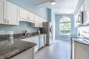 Updated granite kitchen with matching stainless appliances and ivory cabinetry.