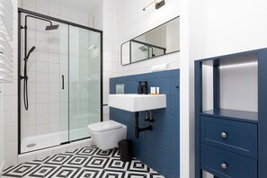 A modern and bright bathroom with white and navy tiles and a shower with rain shower head.