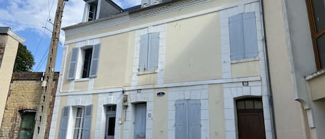 La maison est la porte de gauche avec les fenêtres ouvertes.