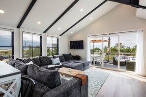 Living room with large sofa, TV and access to the deck 