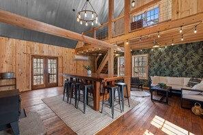 New in 2024, our heated and cooled 4-seasons room features a bar height table with ten stools, come couch, a SWING, wood-burning stove and a foos ball table in the loft.