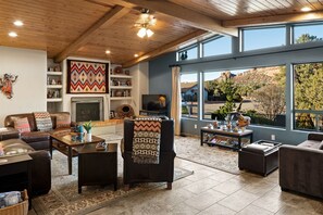 The open living area features warm wood paneled ceilings and large windows with picture perfect views