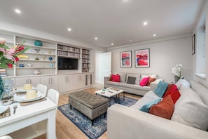 Step into our inviting living area, adorned with pristine white walls that exude a sense of modern elegance. Relax and unwind as you enjoy your favorite shows and movies on the sleek smart TV, providing a world of entertainment at your fingertips.
