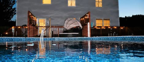 Nighttime view of the pool and back of the home