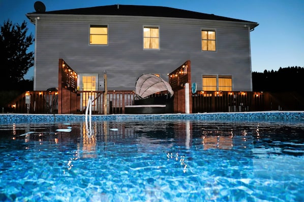 Nighttime view of the pool and back of the home