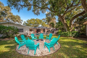 Large private backyard with custom fire pit surrounded by white sea shells.