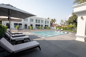 Outdoor swimming pool with sun embrella and pool bench