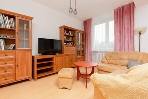  comfortable living area with a wooden entertainment unit, sofa set, and large windows adorned with pink curtains.