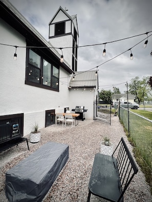 Outdoor lounge area with gas fire pit, grill, & table & night lights