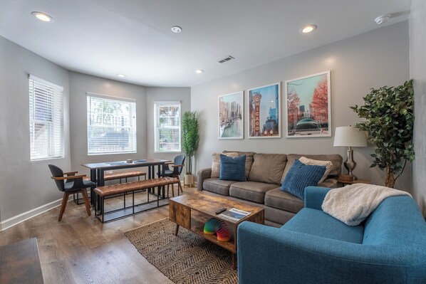 Living room + dining room that has comfortable seating, mounted tv, and games.
