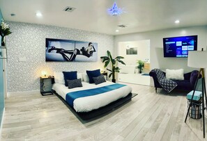 Massive primary bedroom with a king size bed, lounge chair and big screen tv.