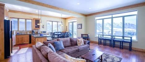 Experience the cozy living room, outfitted with plush seating, a fireplace, an expansive smart TV, and windows that frame the breathtaking mountain vistas.
