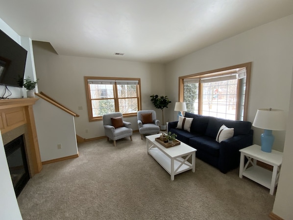 View of living room, with gas fireplace and TV, from walking inside front door