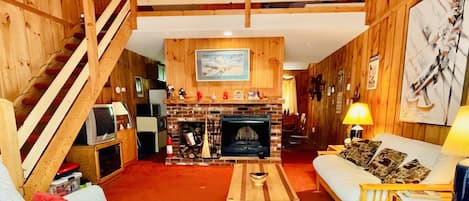 Living room with a wood-burning fireplace, vaulted ceiling, and a Loft