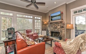 Inviting living room with stone fireplace and forest views.