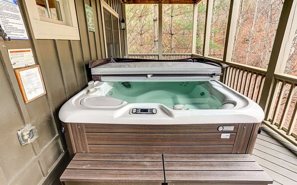Private hot tub on covered deck with serene forest views.