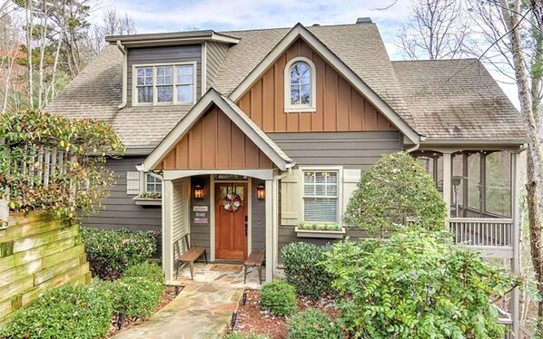 Charming cabin exterior with lush greenery and welcoming porch.