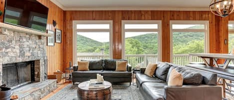 Leather sofas, stone fireplace, mountain view - luxury lodge living.