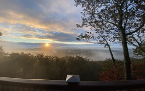 Sunrise over misty mountains seen from a cozy deck; a tranquil dawn.