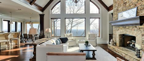 Luxury open-plan living room with mountain views and stone fireplace.