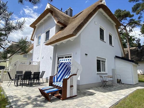 Skandinavisch eingerichtetes Reetdachhaus mit Strandkorb und Außen-Sitzbereichen
