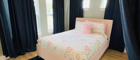 Pink upholstered queen storage bed with room dividing navy blackout curtains