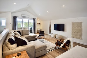 Living room with large sectional sofa, 65”tv, half bath, and desk area.