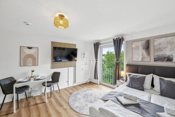 Cozy studio apartment with box spring bed, dining and work table, smart TV and view of the green