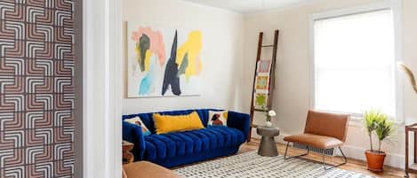 Cozy living room with a large blue velvet couch. Bright and fun. Perfect for lounging or hosting.