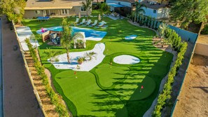 Lush landscaping, artificial turf, white sand, and a giant pergola! 