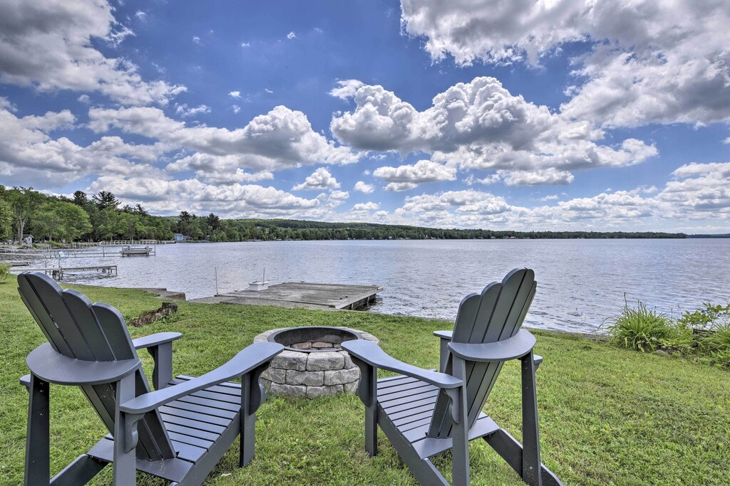 Two chairs sit at a firepit near a lake on a beautiful sunny day at lakefront vacation rental in Vermont