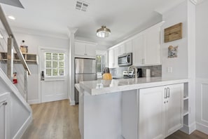 Full kitchen, Front door, and staircase to upstairs bedrooms 