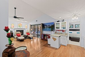 Living room: open concept, 85" TV, seating for everyone, wet bar, fireplace.