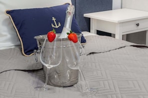 A cozy bed with soft bedding and two wine glasses on a silver tray, creating a romantic vibe.