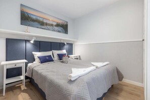 A bedroom with a comfortable double bed adorned with plush bedding and pillows. The room is complemented by a minimalist design and ample natural light.