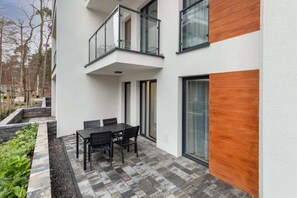 A modern apartment building showcasing clean lines and a balcony. The surrounding greenery adds a touch of tranquility.