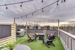 Sprawling rooftop patio with dining table, seating, gas firepit, and custom bar