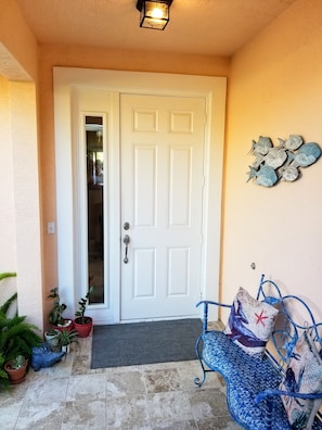 Fully covered and lit front door entryway with tropical décor and succulents.