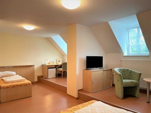 Blick zum Einzelbett, Schreibtisch und kleinem Kühlschrank