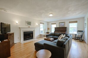 Living Room 1:  Large sectional couch, flat-screen TV, piano, and fireplace.