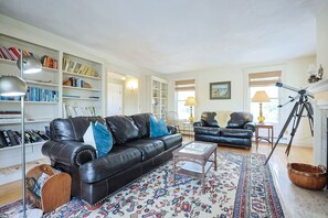 Living Room 2: Leather sofas, fireplace and built-in shelves with books.