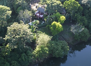 La casa y su vegetacion en vista desde el dron sobre el rio, y la bajada