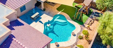 Our Lake Havasu vacation rental has a resort-like backyard with a private pool, kids playground, hot tub, loungers, dining table, and abundant seating.