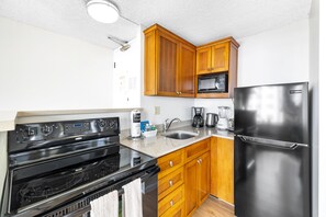 Fully equipped kitchen with essential appliances such as coffee maker, microwave, stove, and refrigerator.