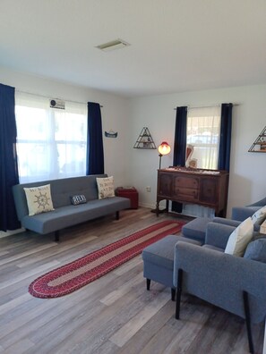 Living room with twin size futon. Sheets, blanket and pillow in 2 drawer chest.