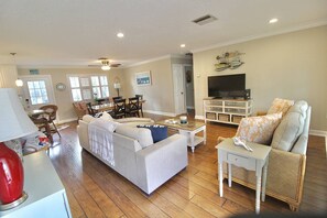 Inside the front door is a bright, beautiful open floor plan with coastal decor, plantation shutters and wood flooring.