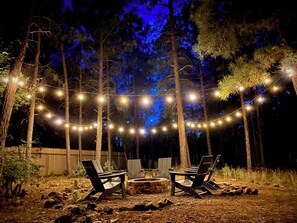 Cantina lights surround the fire pit in the backyard. More chairs are available 