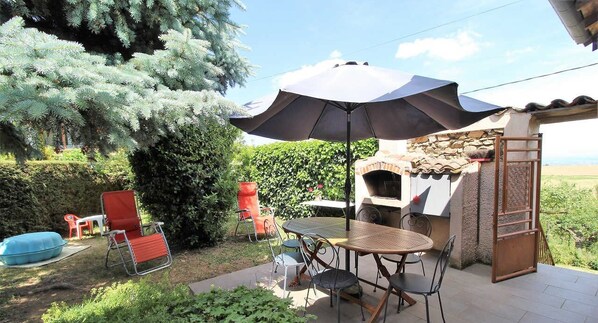 Gîte "La Colline Fleurie" à Rontalon, dans le Lyonnais - Rhône : la terrasse et portillon d'accès au pré avec portique en contrebas.